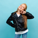 girl in a leather jacket and jeans posing on a light blue background with copyspace - PhotoDune Item for Sale