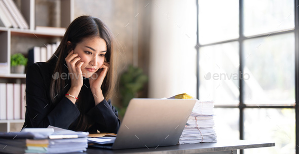 Young Asian businesswoman working on laptop computer, stressed has a headache and thinks hard from - Stock Photo - Images