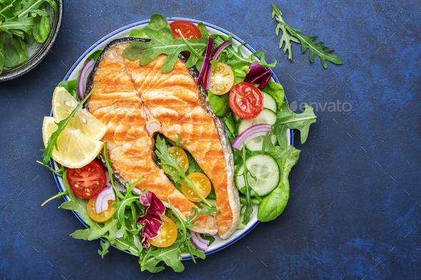 Grilled salmon steak with vegetables, tomatoes, arugula and lettuce side dish salad  - Stock Photo - Images
