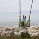 Little girl swinging against the scene of Nazare coast in Portugal - PhotoDune Item for Sale