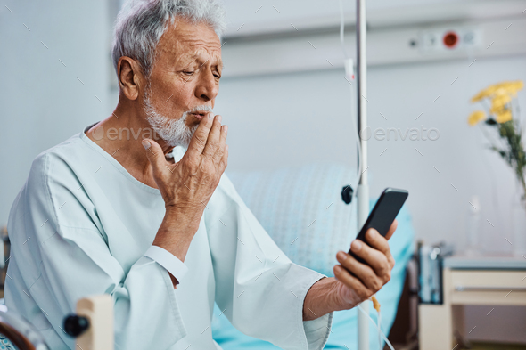 Senior patient sending a kiss during video call from hospital ward.