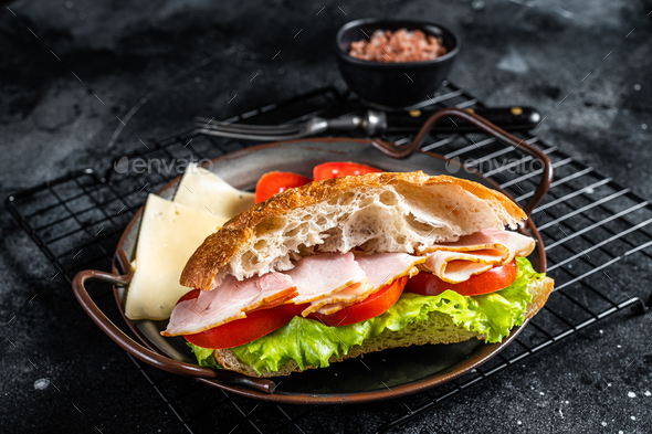 Deli meat sandwich with turkey ham, cheese, tomato and Lettuce. Black background. Top view