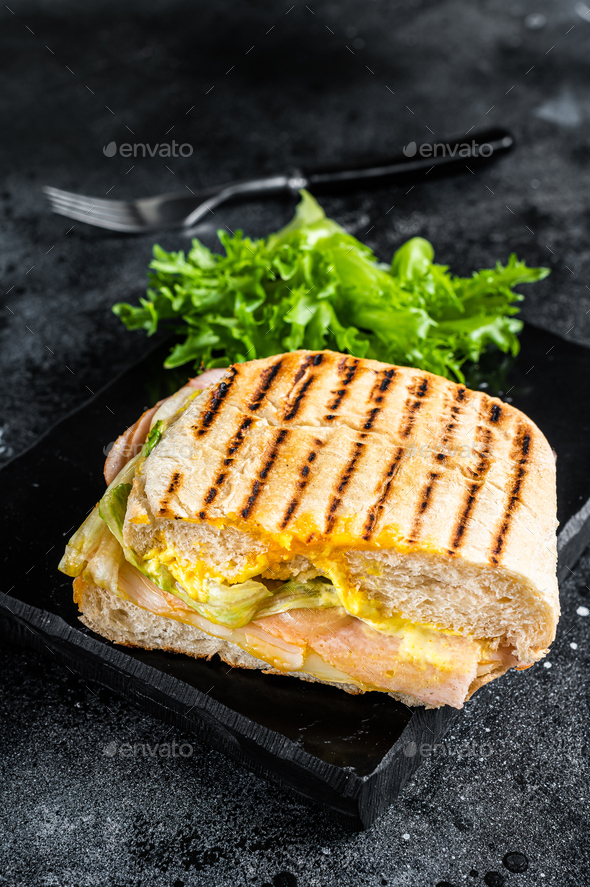 Club sandwich panini with ham, tomato, cheese and basil. Black background.  top view Stock Photo by composter-box