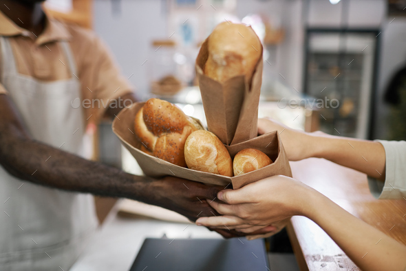Bakery Worker Giving Packagers to Customer - Stock Photo - Images