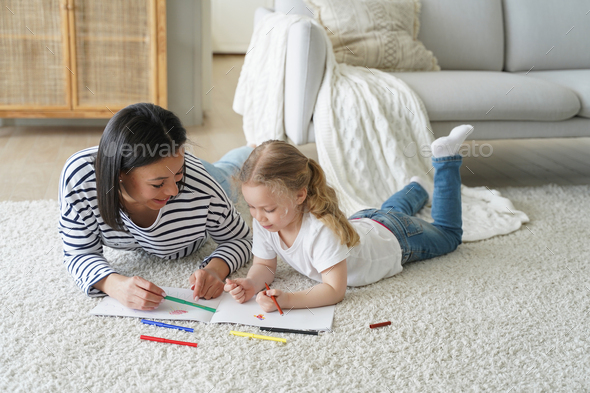 Kid girl daughter and mom drawing painting lying on floor carpet together. Children's education - Stock Photo - Images