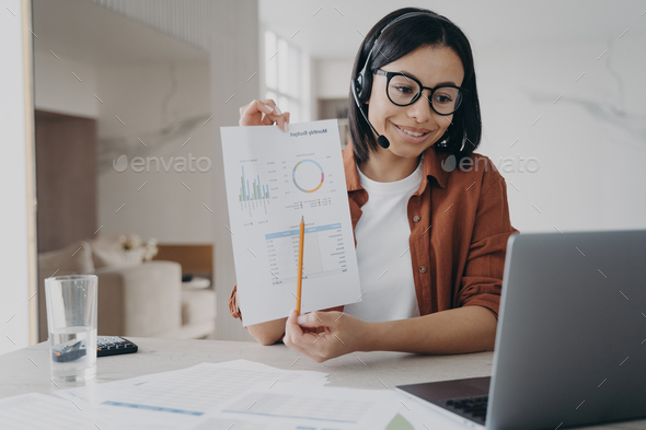 Businesswoman in headset showing chart, discussing business project while video conference at laptop - Stock Photo - Images