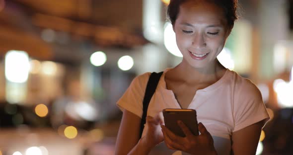 Woman watching on mobile phone at outdoor  alt