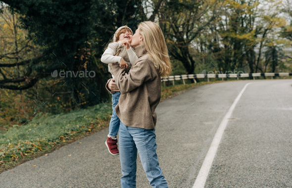 A cheerful young mother is spinning in embracing with her little daughter on a walk. - Stock Photo - Images