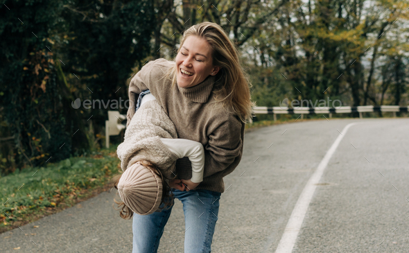 Laughing mother circling her little daughter in her arms on a rural road. - Stock Photo - Images