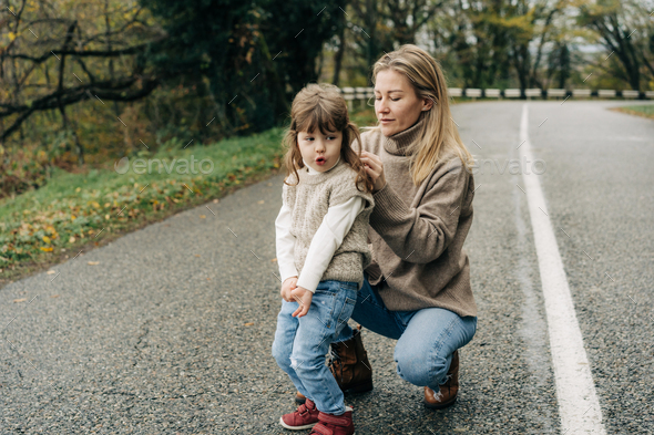 Mom braids the hair of a cute little daughter on a walk in the countryside. - Stock Photo - Images