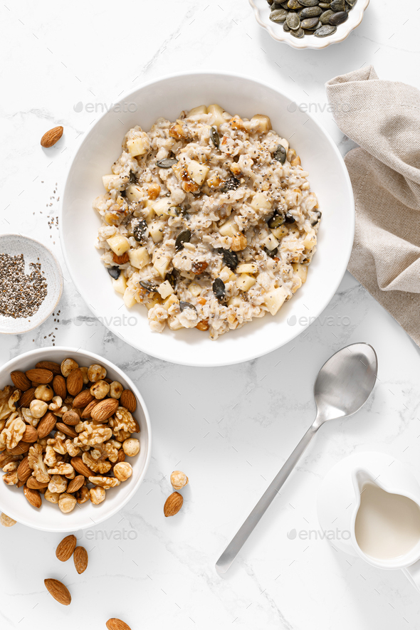 Oatmeal bowl. Oat porridge with nuts, apple, chia seeds and pumpkin seeds for healthy breakfast - Stock Photo - Images