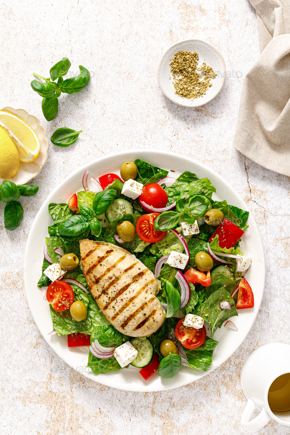 Grilled chicken fillet and fresh green leafy vegetable salad with tomatoes, red onion, olives - Stock Photo - Images