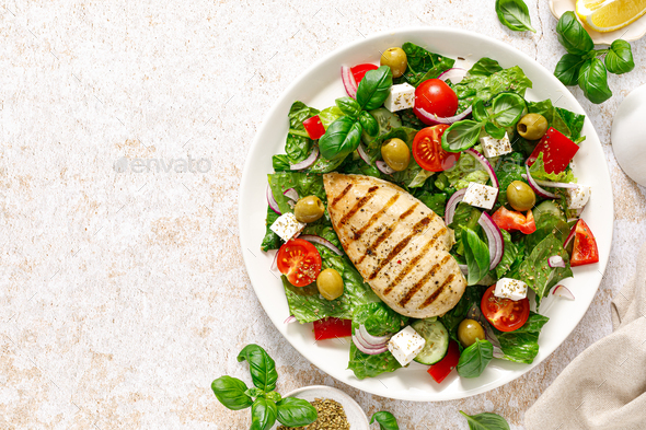 Grilled chicken fillet and fresh green leafy vegetable salad with tomatoes, red onion, olives - Stock Photo - Images