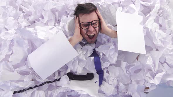Malicious Man Office Worker in Glasses Cries in a Large Heaps of Crumpled Paper alt