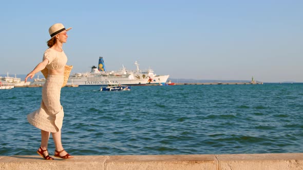Happy woman in a dress walking along the embankment in the city. Split, Croatia alt