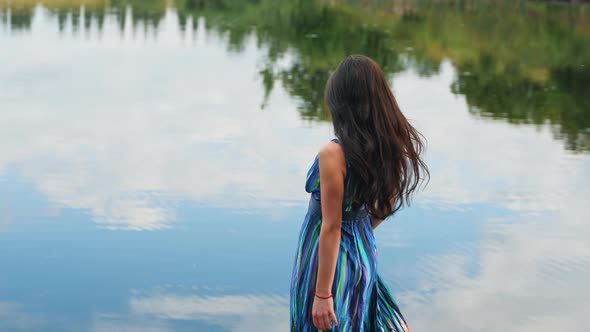 Pretty Brunette Woman in a Beautiful Dress Enjoys Nature