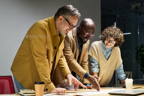 Group of three intercultural brokers discussing financial document - Stock Photo - Images