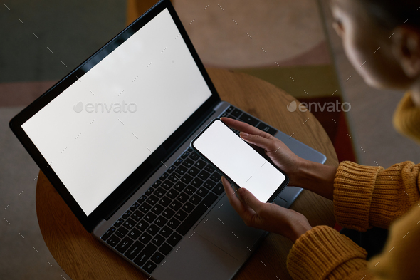 view at young woman using laptop and phone with blank screen mockups - Stock Photo - Images