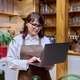 Middle-aged woman in an apron working in restaurant, using laptop - PhotoDune Item for Sale