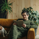 Caucasian man with book and dog sits in sofa at home - PhotoDune Item for Sale