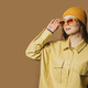 Stylish teenager girl in shirt and hat with sunglasses on brown background - PhotoDune Item for Sale