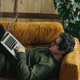 thirty-year-old man with laptop sitting at home on the couch - PhotoDune Item for Sale