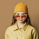 Stylish teenager girl in shirt and hat with sunglasses on brown background - PhotoDune Item for Sale