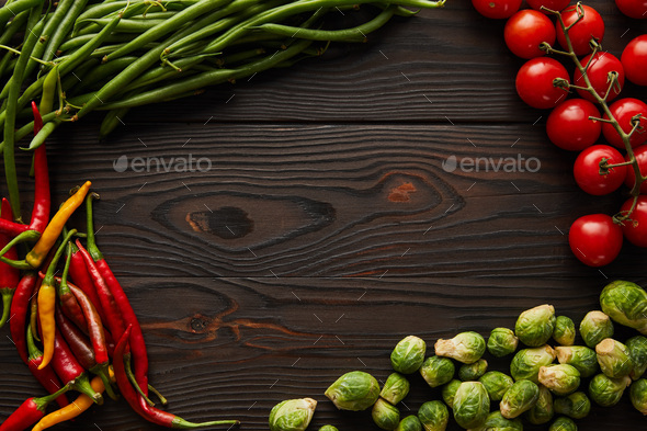 top view of chili peppers, cherry tomatoes, green peas, brussels sprouts on wooden table