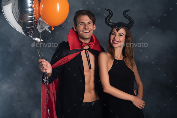 attractive woman with horns holding flogging whip near man in