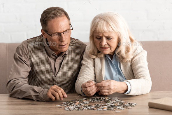 selective focus of senior couple with mental illness matching puzzle pieces