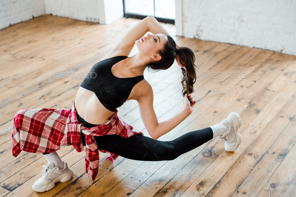 young flexible woman posing while dancing jazz funk in dance studio