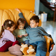 Сhildren sit on a leather sofa in the living room and watch cartoons on phone. - PhotoDune Item for Sale