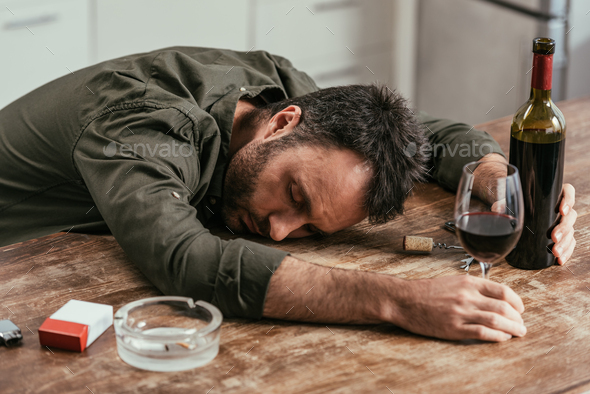 Drunk man sleeping on table with wine and cigarettes Stock Photo by ...