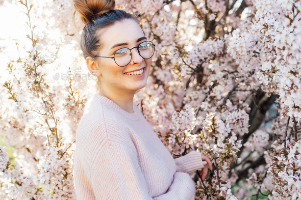 Portrait of young smiling caucasian hipster girl in glasses with pimples, acne on her face.