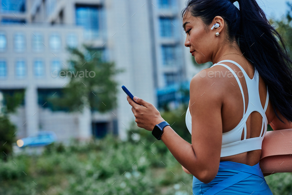 Woman with bluetooth earphones using cellphone after training