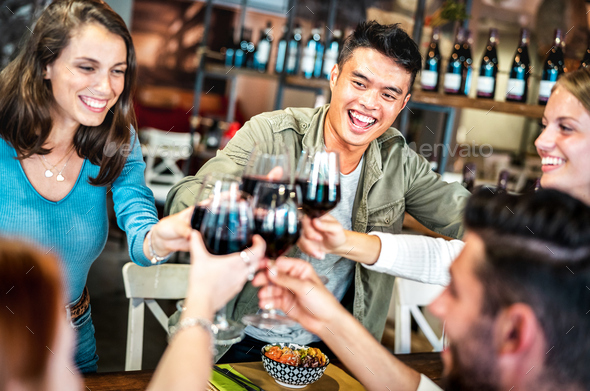 Trendy multicultural friends toasting red wine at sushi poke bowl restaurant - Stock Photo - Images