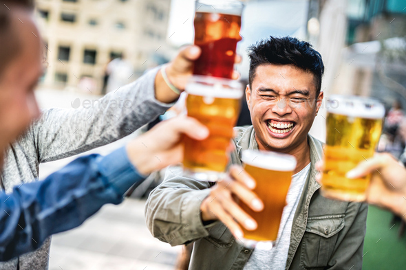 Group of happy multicultural young people drinking and toasting beer together - Stock Photo - Images