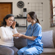 Young female physician leaning forward to elderly lady patient holding her hand in palms. supporting - PhotoDune Item for Sale
