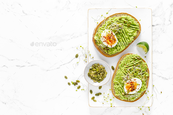 Avocado toast with boiled egg, seeds and sprouts on white background. Healthy diet food. Top view - Stock Photo - Images