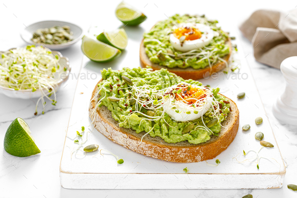 Avocado toast with boiled egg, seeds and sprouts on white background. Healthy diet food - Stock Photo - Images