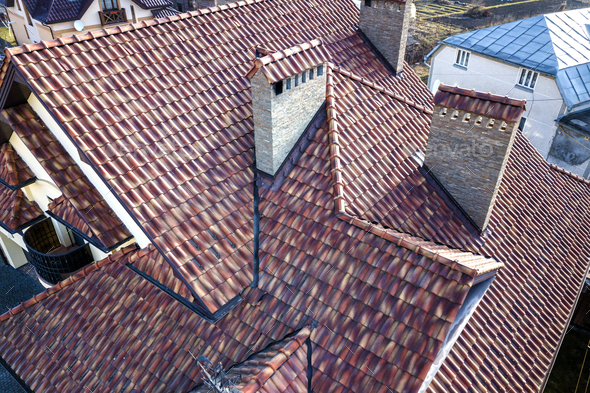 Aerial top view of complex house metal shingle roof and high brick chimneys.