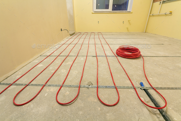 Heating red electrical cable wire installation on cement floor in small new unfinished room
