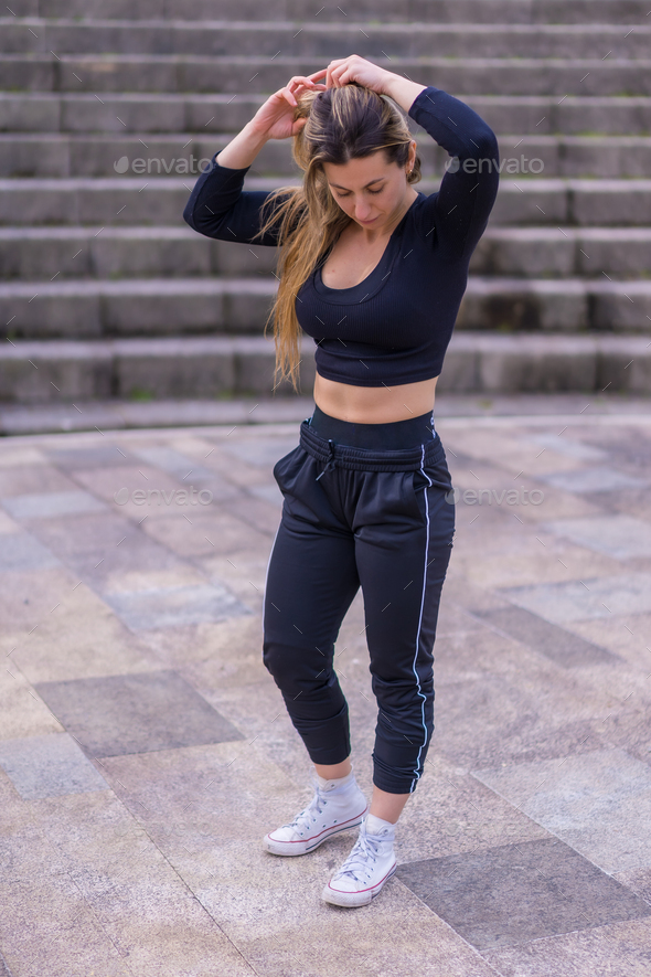 Caucasian young woman doing fitness in a city park, portrait in spring exercise dressed in black