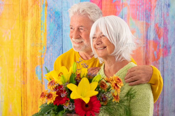 Attractive pleased elderly woman receives flowers as present for anniversary of Valentine day