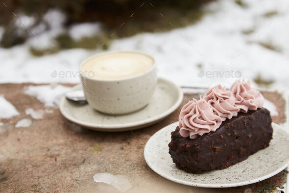 Vegan brownie cake with cup of cappuccino outside. Coffee with dessert. Winter aesthetics