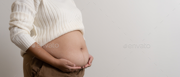 An obesity carrying her chubby belly to show the concept of unhealthy fat woman.