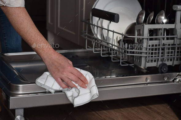 Woman cleaning sides of dishwasher door with dish cloth