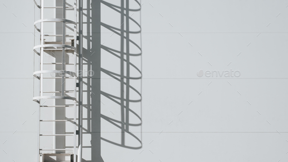 Steel fire escape on background of white wall of sandwich panels outdoors, copy space.