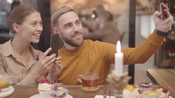 Young Man and Woman Making Photos in Restaurant alt