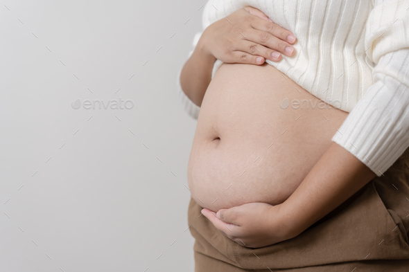 An obesity carrying her chubby belly to show the concept of unhealthy fat woman.